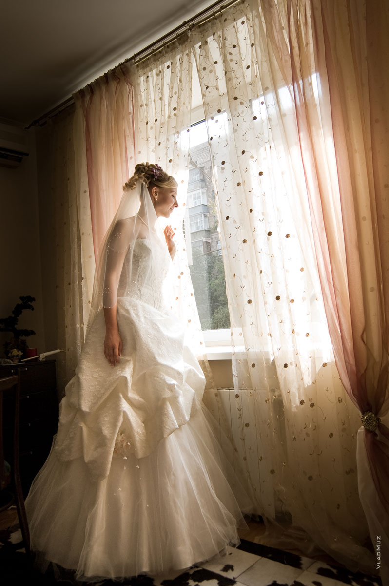 Фото невесты, стоящей у окна в ожидании жениха