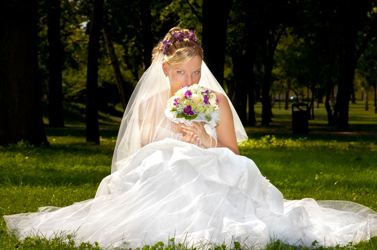 Фотография невесты с букетом, сидящей на лужайке