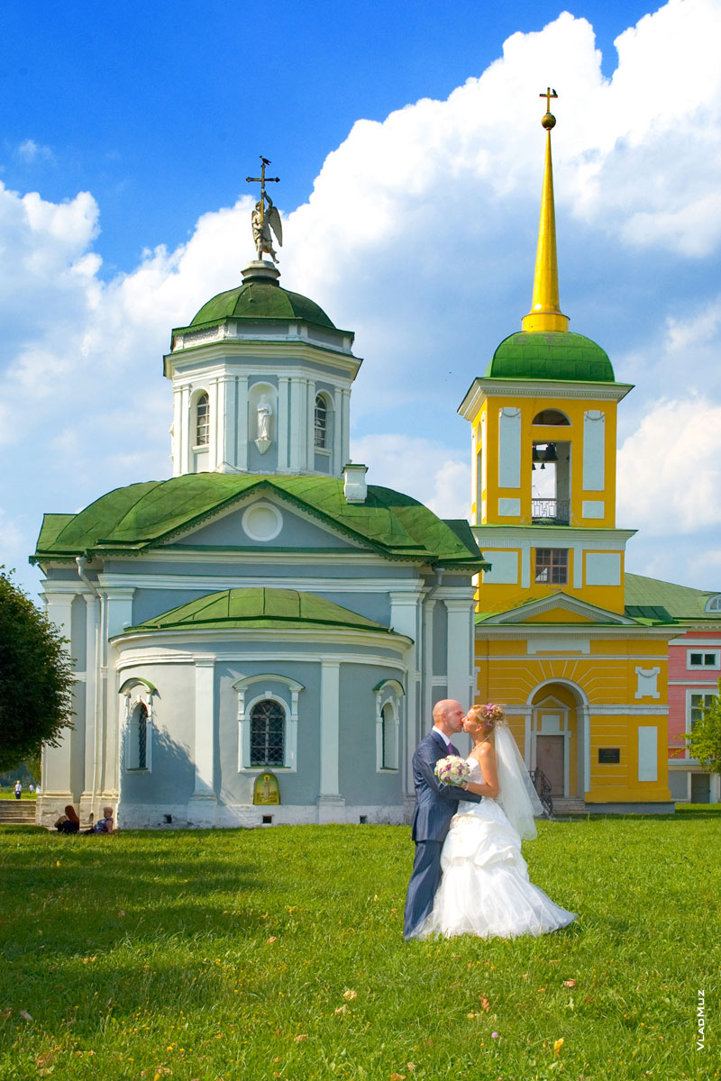 Свадебный этюд: фото поцелуя новобрачных на фоне церкви и колокольни усадьбы Кусково