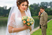 Свадебный этюд № 1: невеста стоит на переднем плане с букетом, вдали жених говорит по телефону