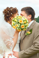 Интересное свадебное фото: жених с невестой целуются, закрываясь свадебным букетом невесты
