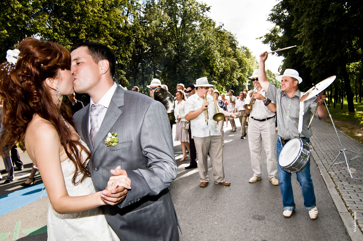 Жених с невестой танцуют и целуются на Поклонной горе в Москве, рядом во всю играет оркестр