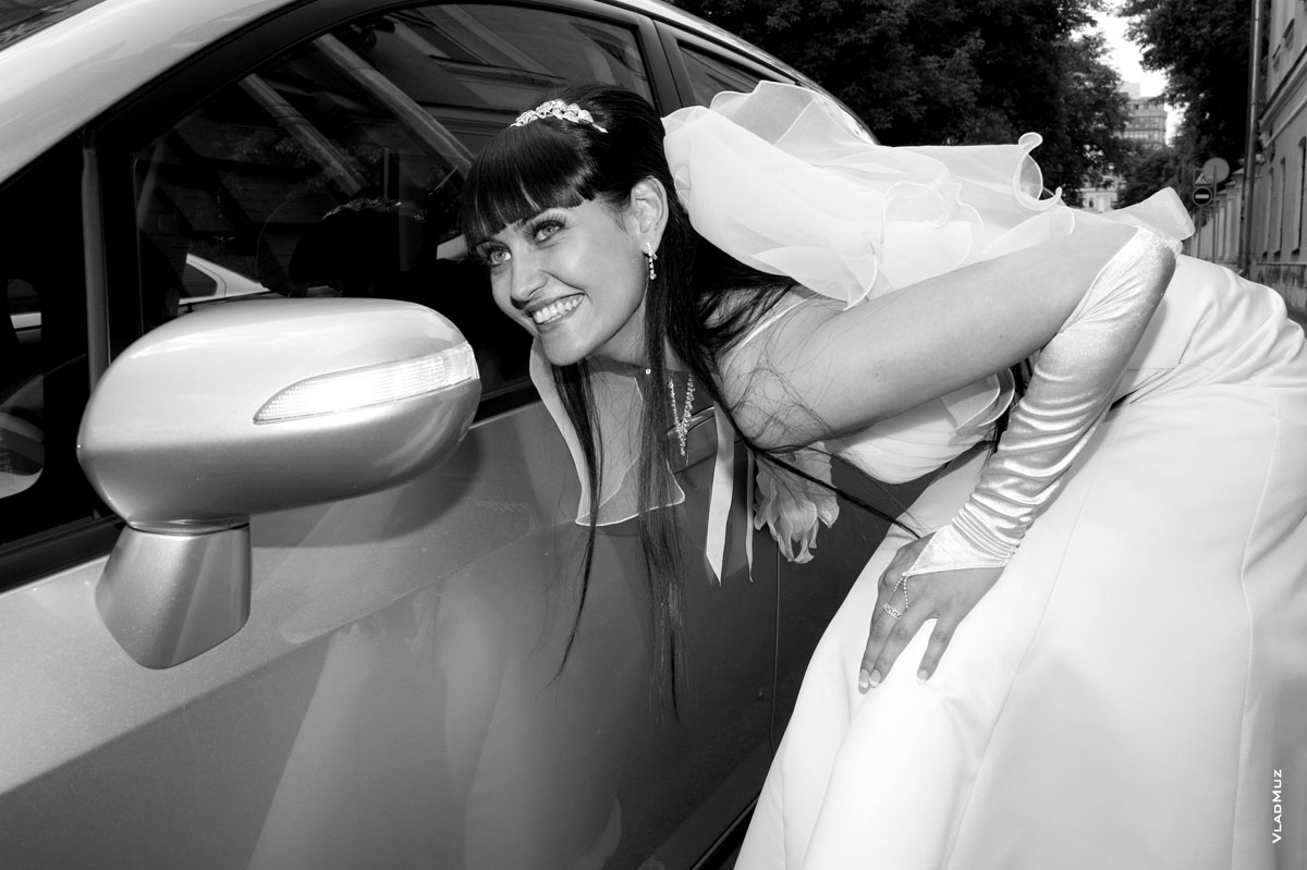 Фото улыбающейся невесты перед зеркалом заднего вида автомобиля