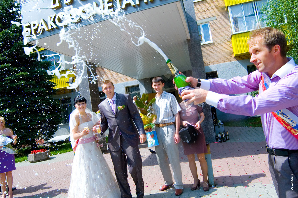 Фото брызг шампанского на фоне молодоженов и Дворца бракосочетаний в Мытищах