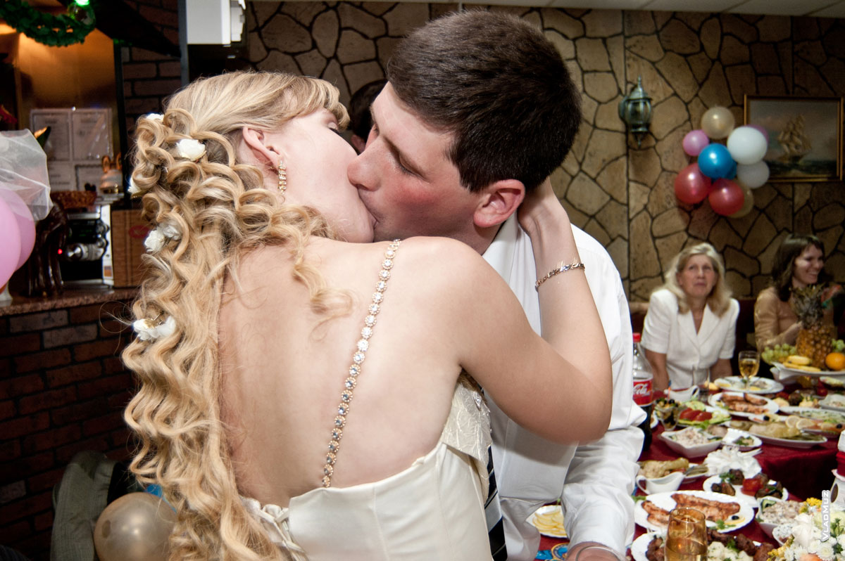 Заключительный свадебный поцелуй новобрачных в кафе-ресторане