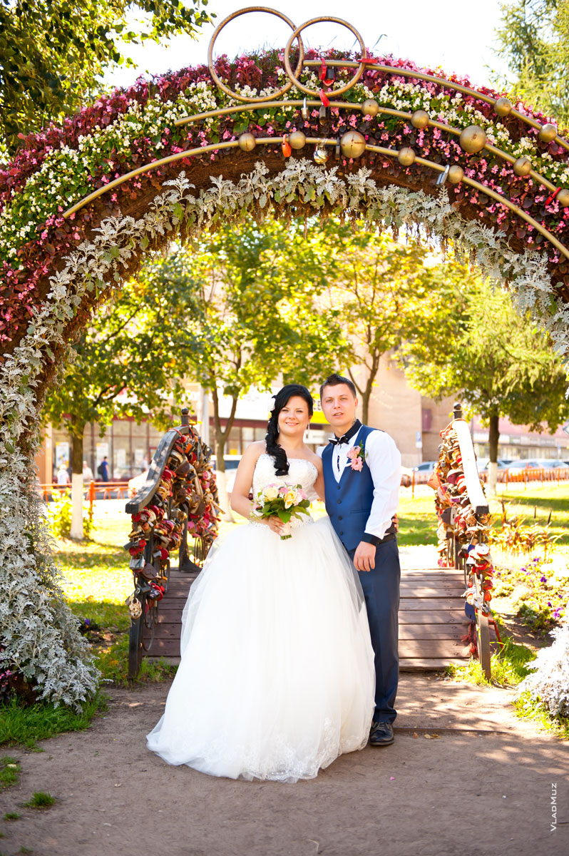 Фото жениха с невестой в цветочной свадебной арке на проспекте Королёва