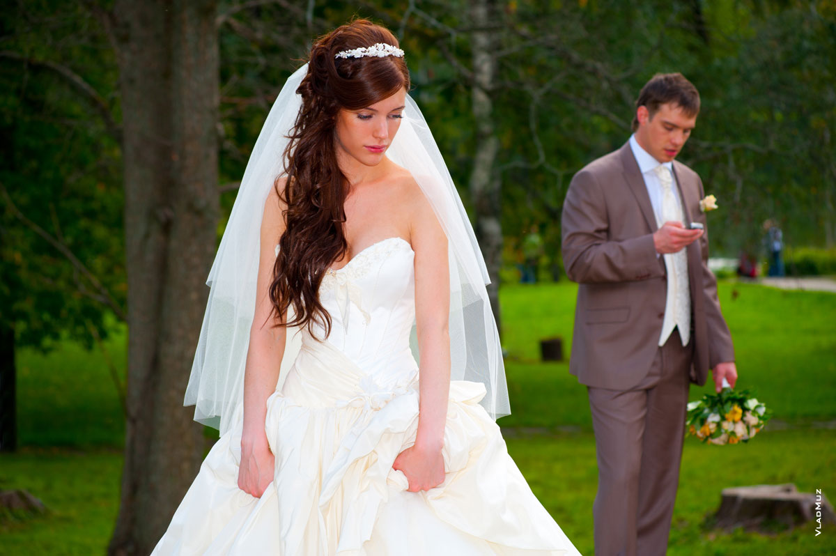 Фото грустной невесты на переднем плане, вдали жених говорит по телефону