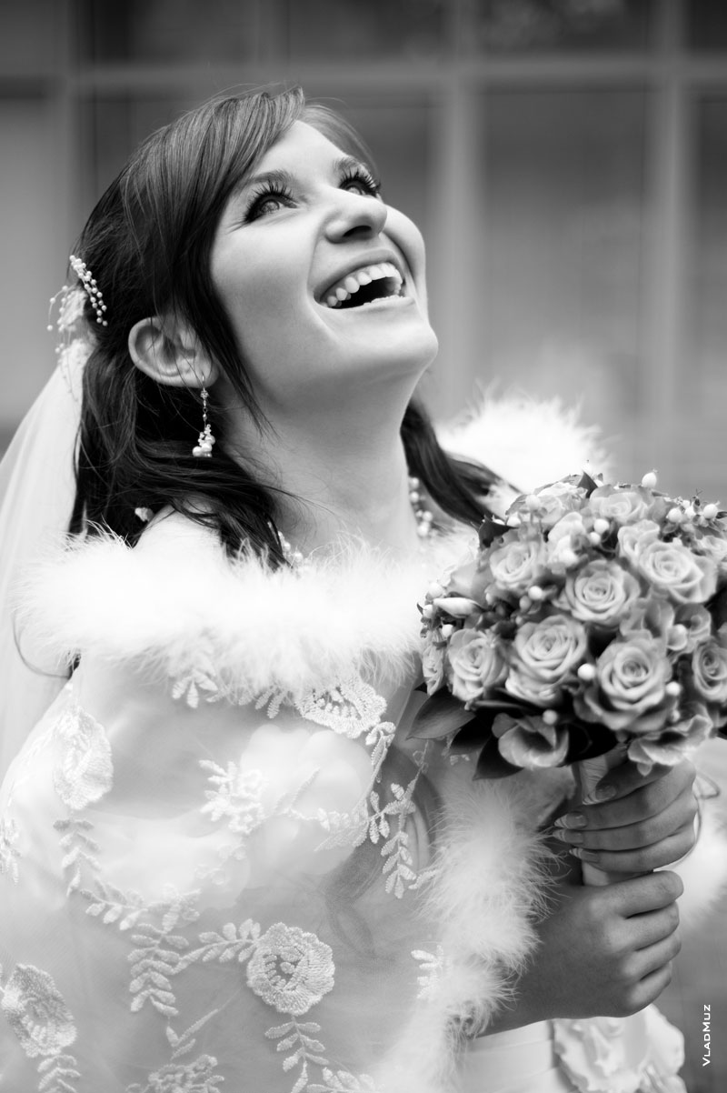Свадебный черно-белый фотопортрет смеющейся невесты с букетом