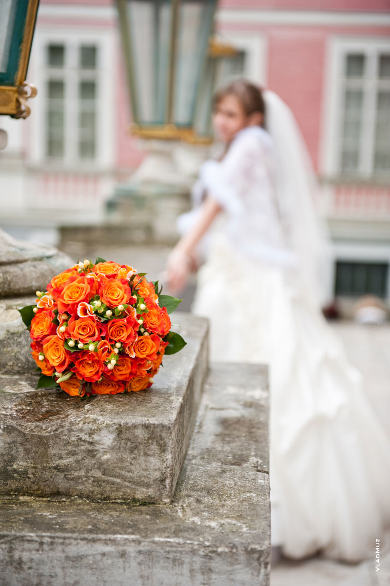 Фото яркого букета невесты на переднем плане, вдали — невеста