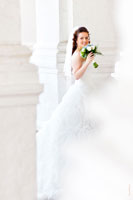 Фото веселой невесты с букетом на фоне белых стен и арок храма Вознесения Господня в Коломенском