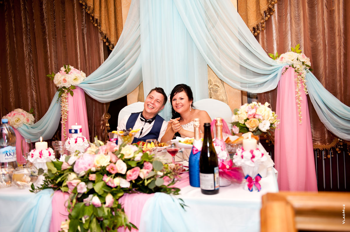 Фото жениха с невестой, сидящих в ресторане за свадебным столом