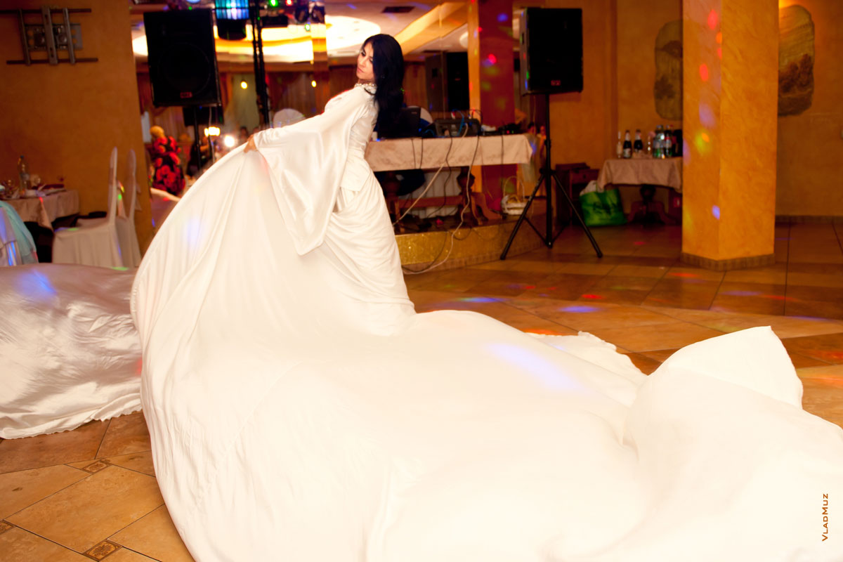 Фото девушки в танце и большого шлейфа белого платья на танцполе в ресторане