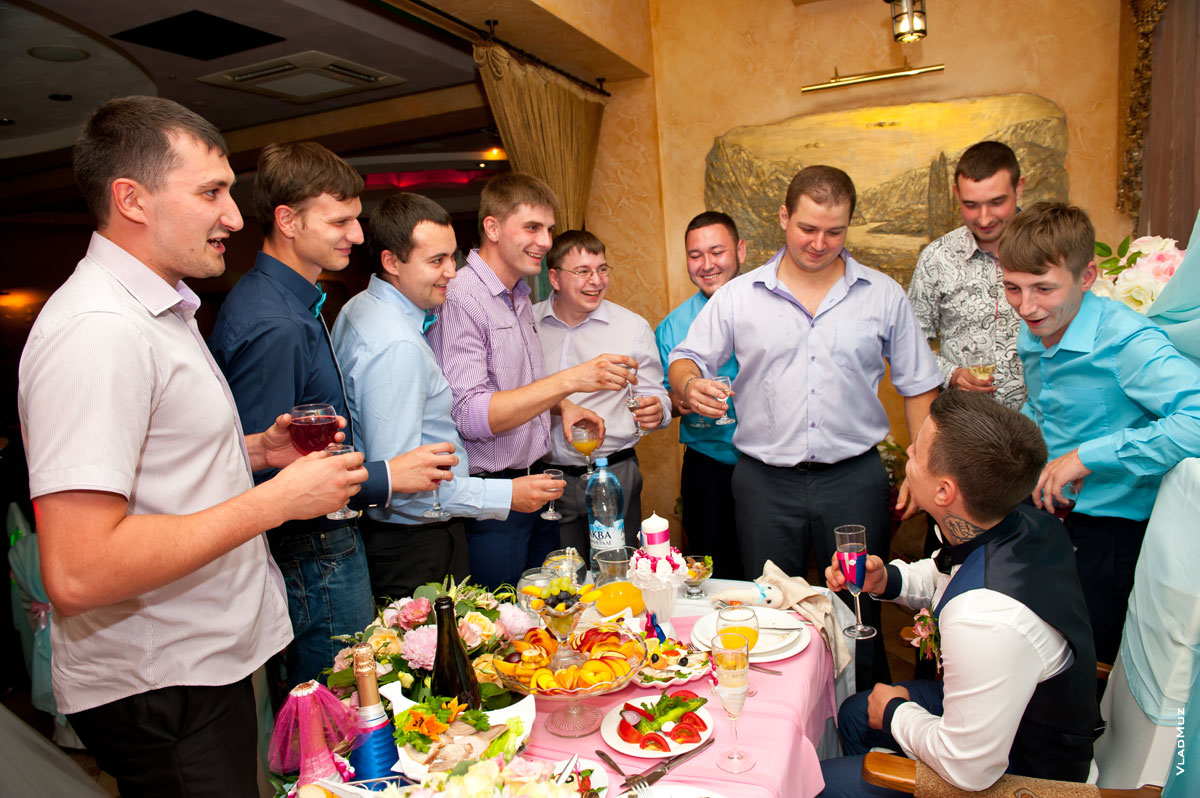 Фото друзей за свадебным столом жениха, поднимающих тост