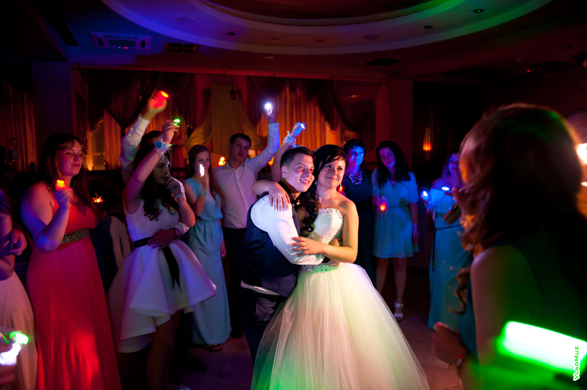 Финальный свадебный танец жениха и невесты в окружении друзей и гостей со светодиодными фонариками в руках