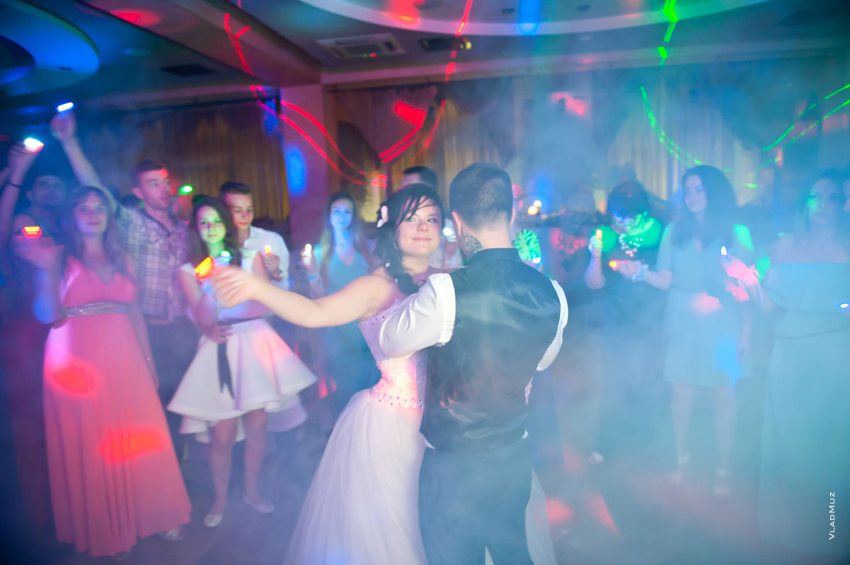 Заключительная фотография из свадебной фотосессии: в кадре дым, огни светодиодов и счастливая невеста с женихом