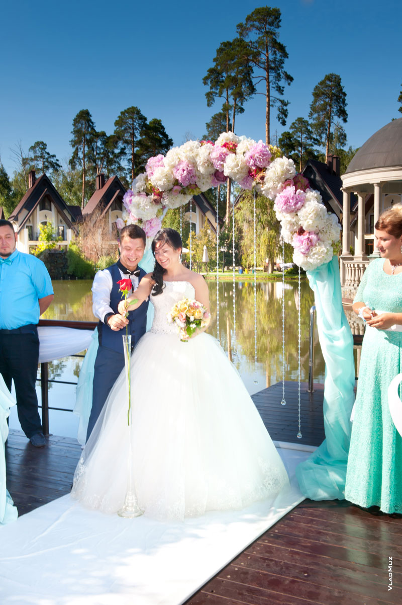 Фото жениха с невестой, устанавливающих розу в вазу