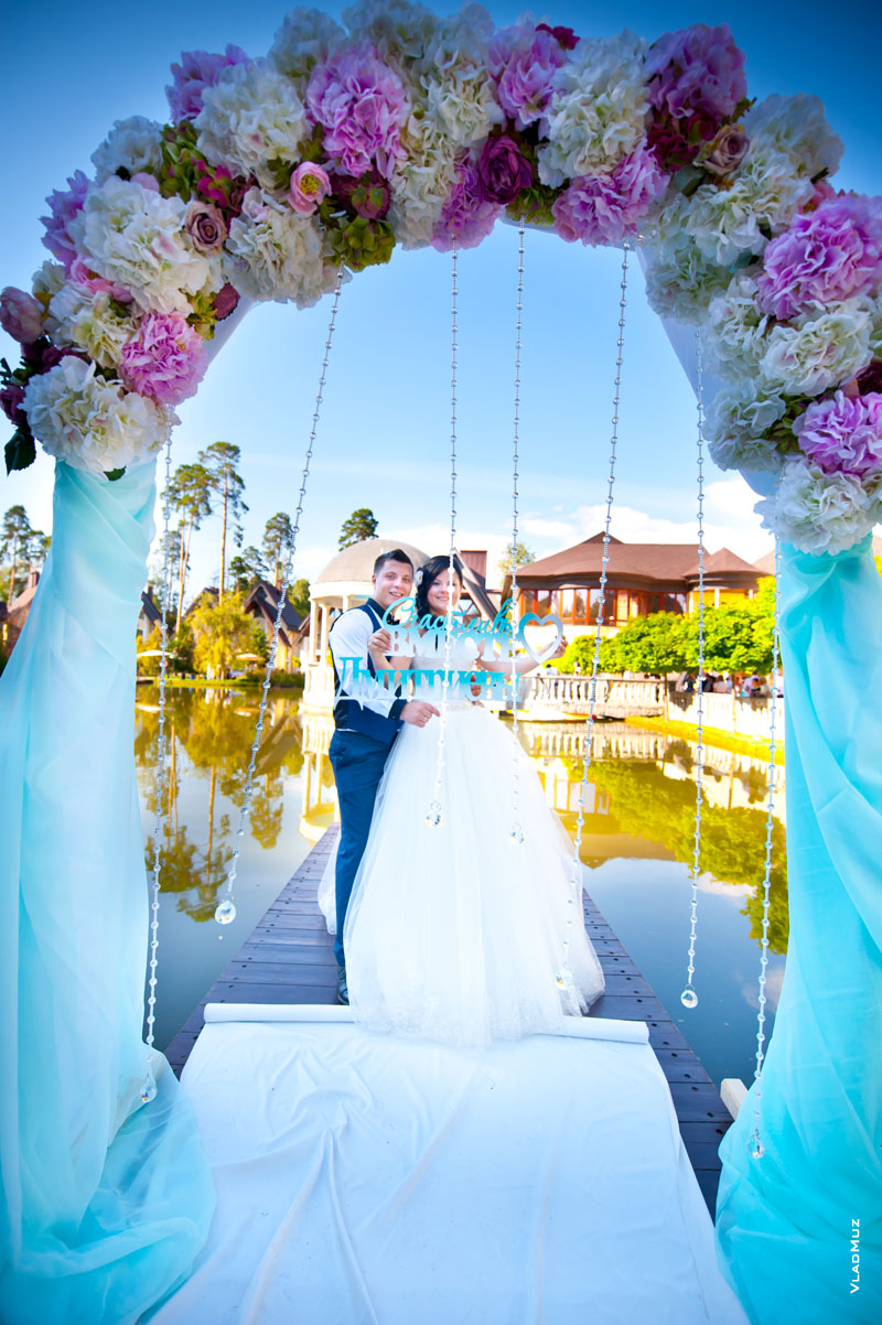 Фото жениха с невестой в свадебной арке и буквами «Счастливы вместе»