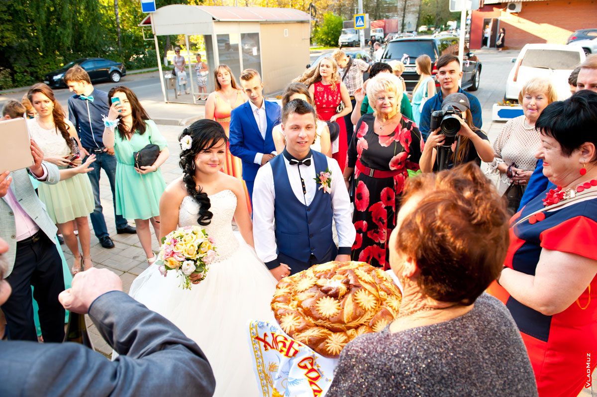 Фото жениха с невестой перед традиционным караваем на входе в ресторан