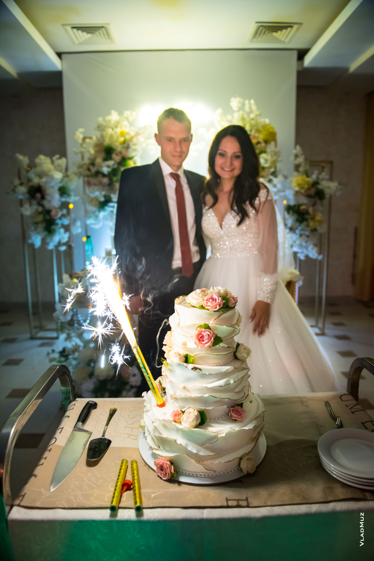 Фото свадебного торта с горящей бенгальской свечой перед женихом и невестой