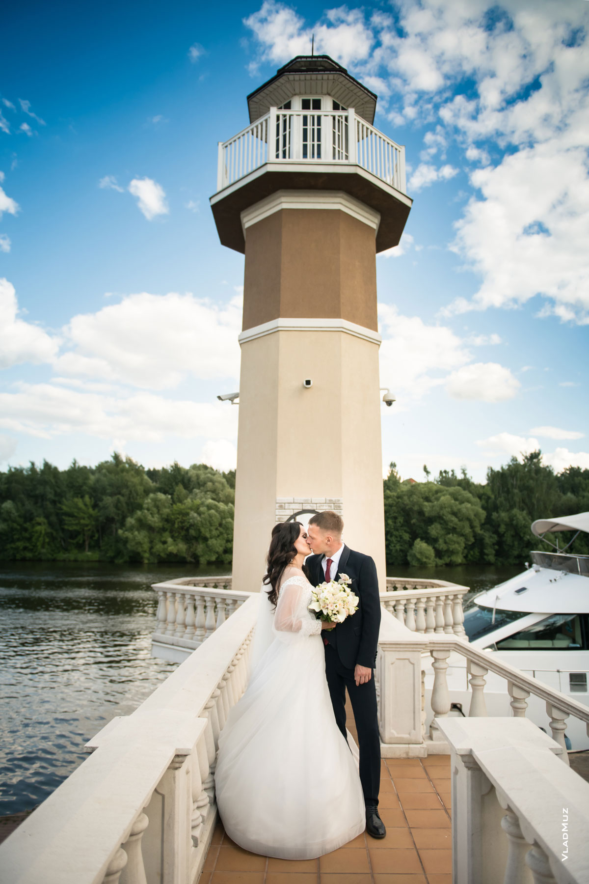 Фото свадебного поцелуя жениха и невесты на фоне маяка ресторана «Белый берег»