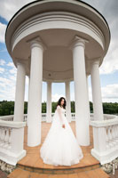 Фото невесты в полный рост в свадебном платье на фоне белой ротонды