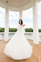 Фото невесты в полный рост в свадебном платье, кружащейся внутри ротонды