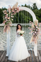 Фото красивой и счастливой невесты с букетом в полный рост в свадебной арке