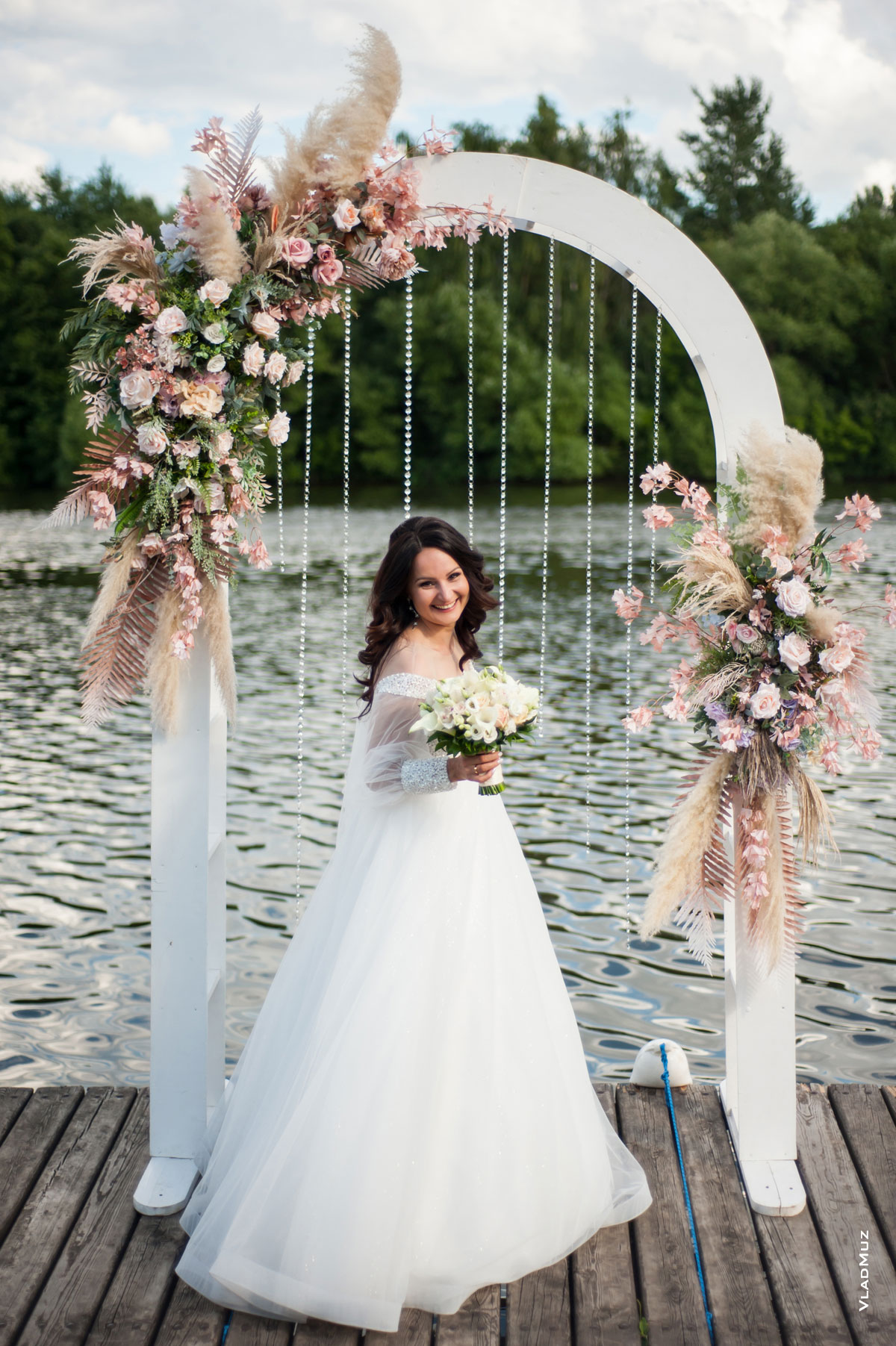 Фото смеющейся невесты с букетом в полный рост в свадебной арке