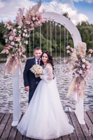 Фото жениха с невестой в полный рост в свадебной арке на берегу реки