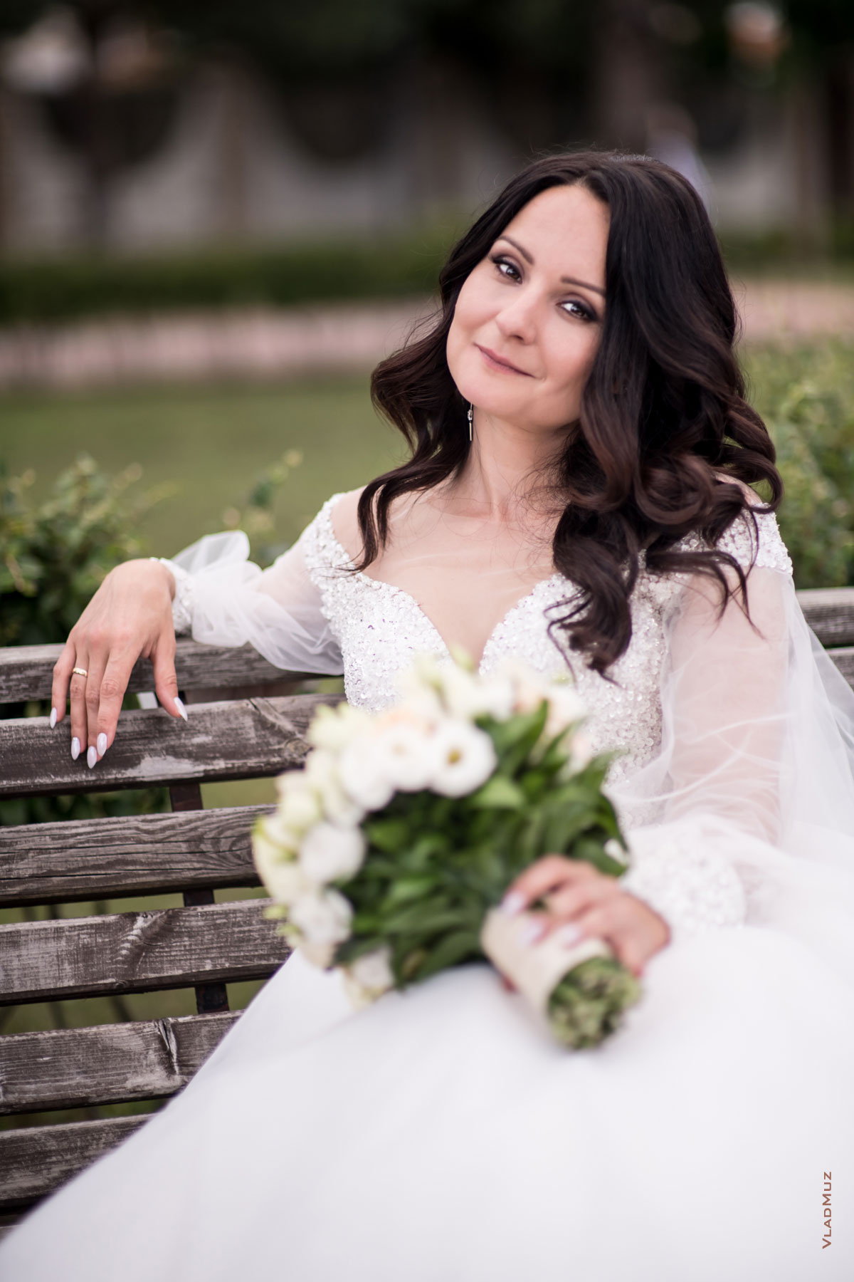 Фото красивой невесты с букетом, сидя на лавочке