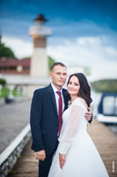 Поясное фото жениха и невесты на фоне маяка и синего неба