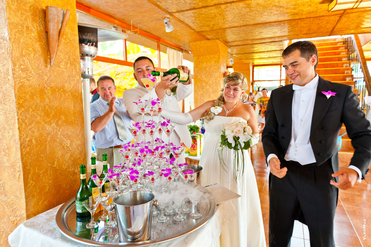 Фото жениха и невесты, наполняющих шампанским пирамиду бокалов в «Малибу», Пирогово