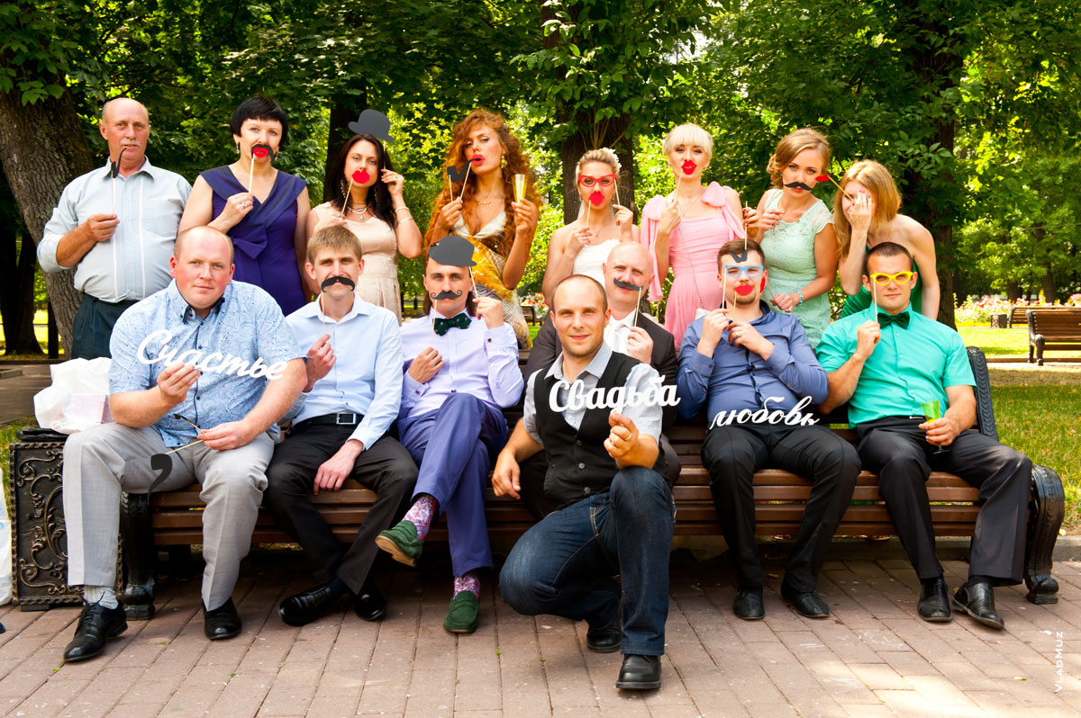 Веселое групповое свадебное фото друзей, гостей и молодоженов на лавочке в Екатерининском парке Москвы