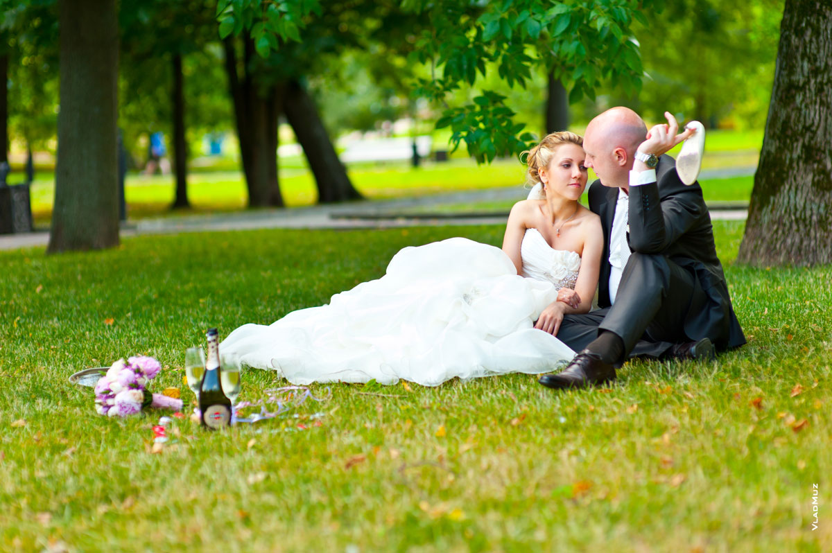 Фото жениха и невесты в парке на траве, рядом стоит бутылка Martini с бокалами и свечи