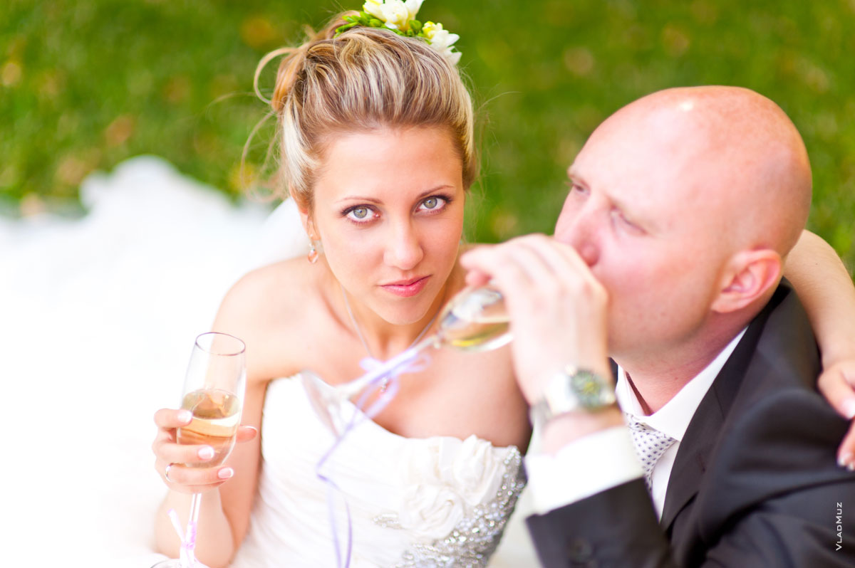 Фото невесты с бокалом шампанского, рядом жених — в расфокусе