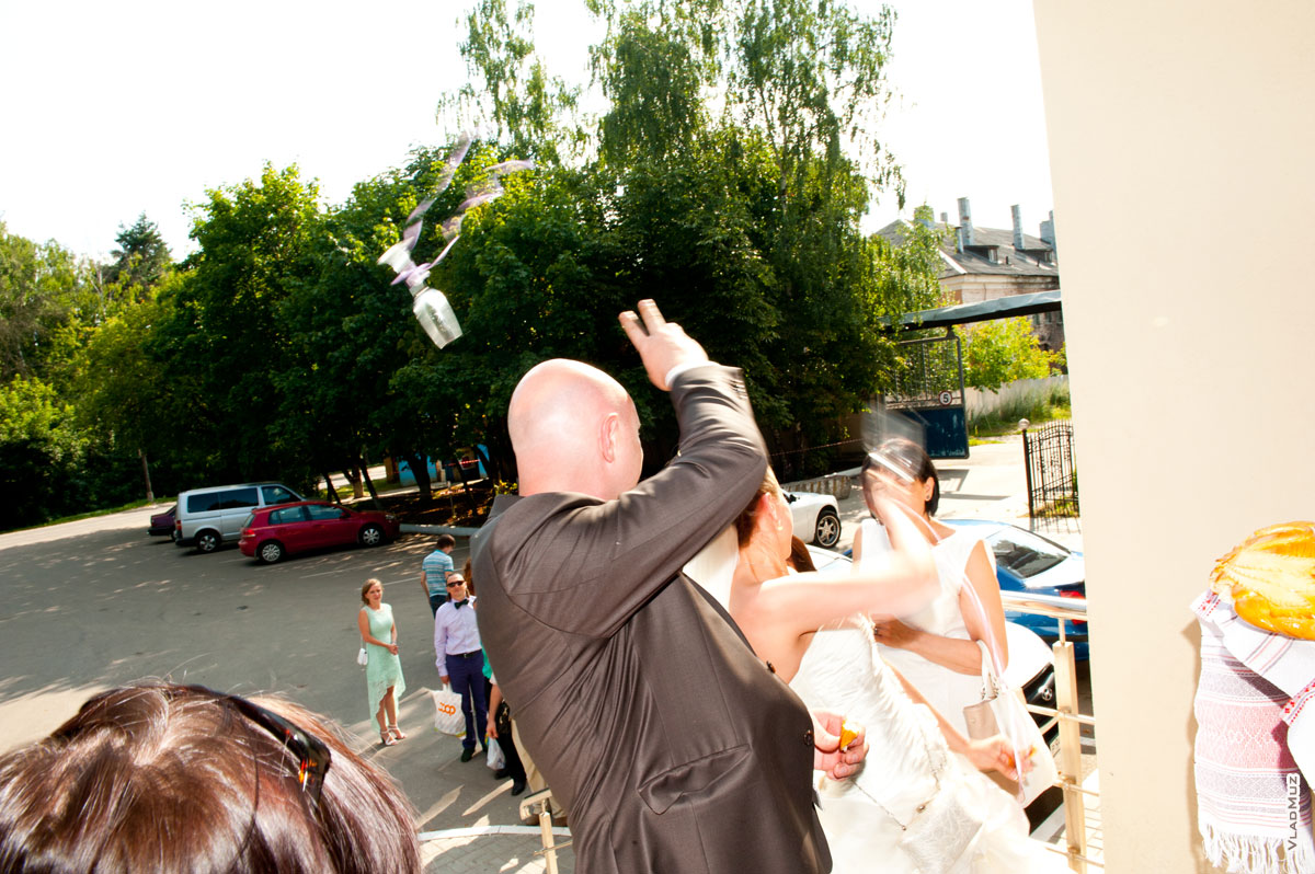 На фото жених с невестой бросают свадебные бокалы на счастье