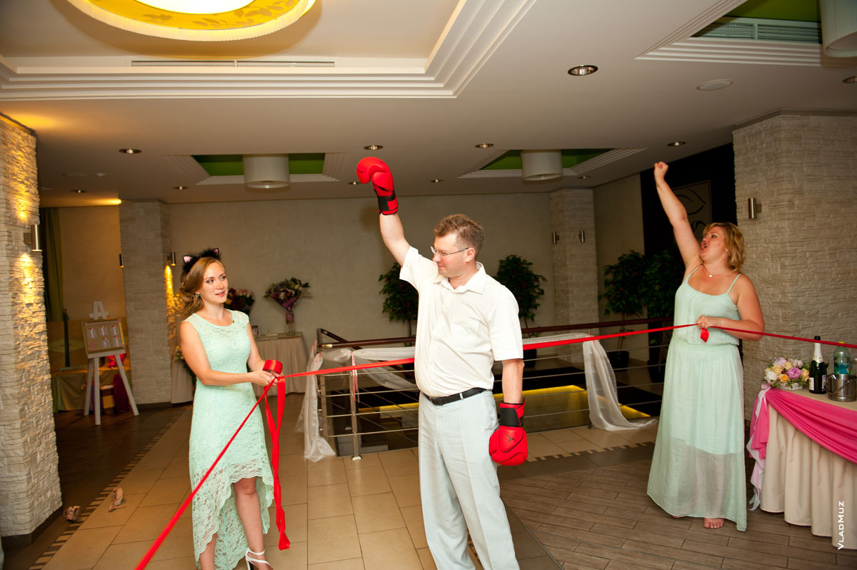 Фото свадебного конкурса в боксерских перчатках. Девушки в углах ринга держат канаты