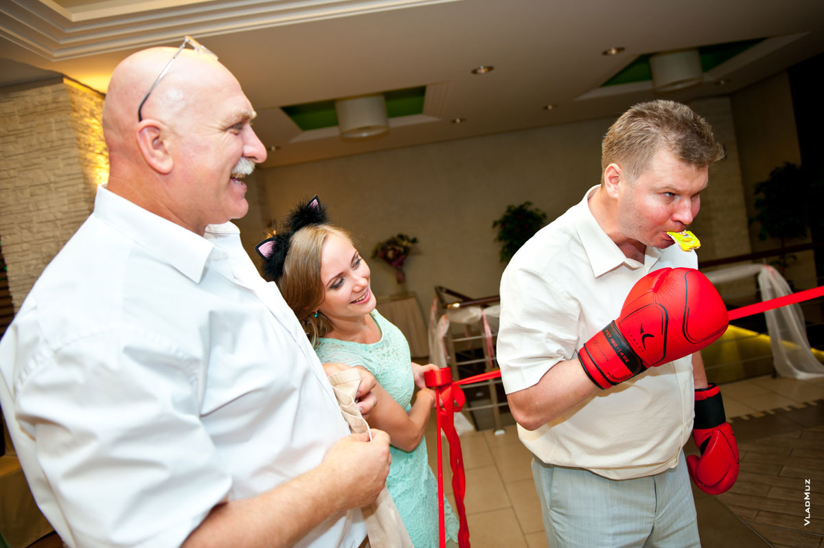 Фото свадебного конкурса: нужно раскрыть и съесть конфету в боксерских перчатках