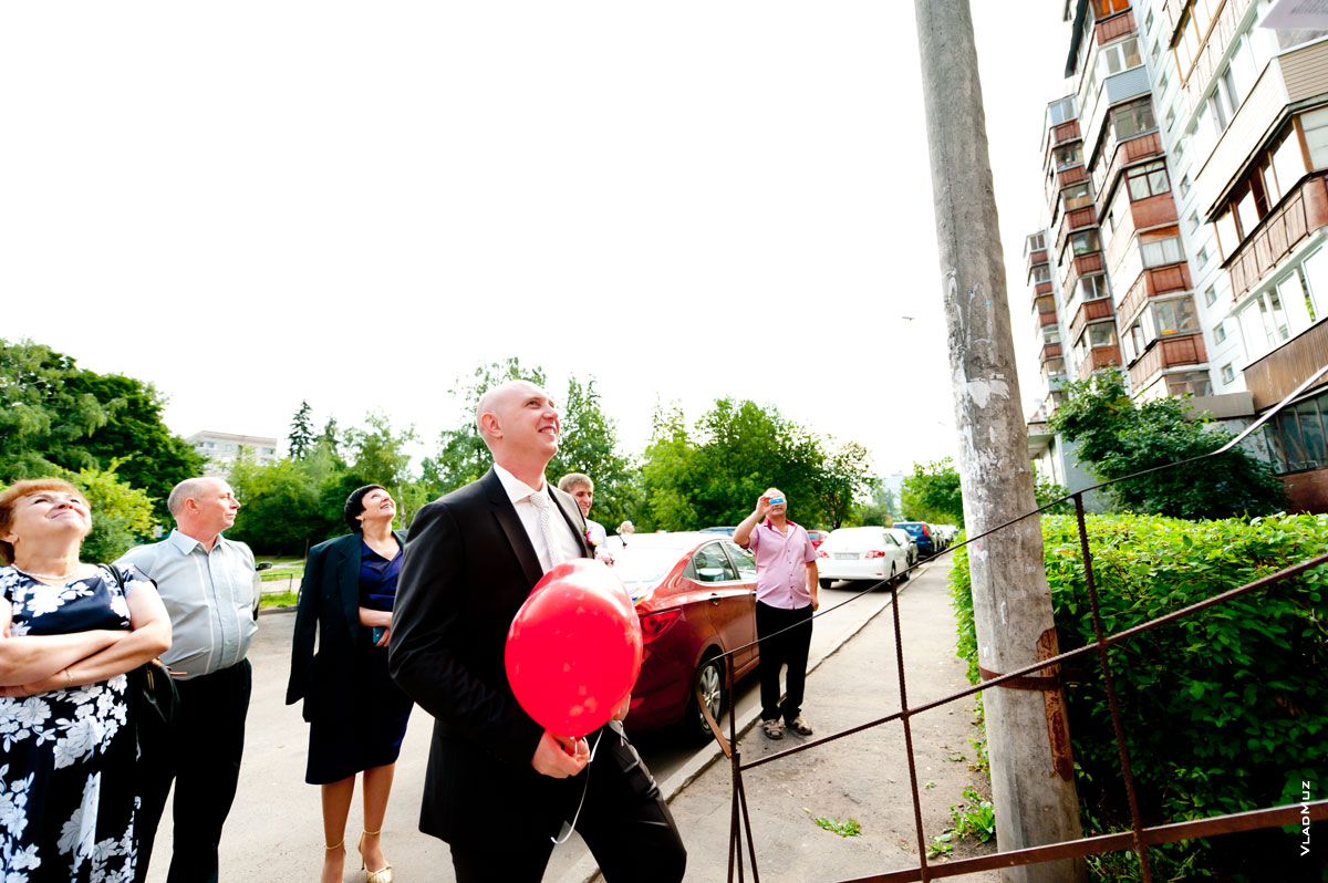 Фото жениха с красным воздушным шаром перед входом в дом невесты