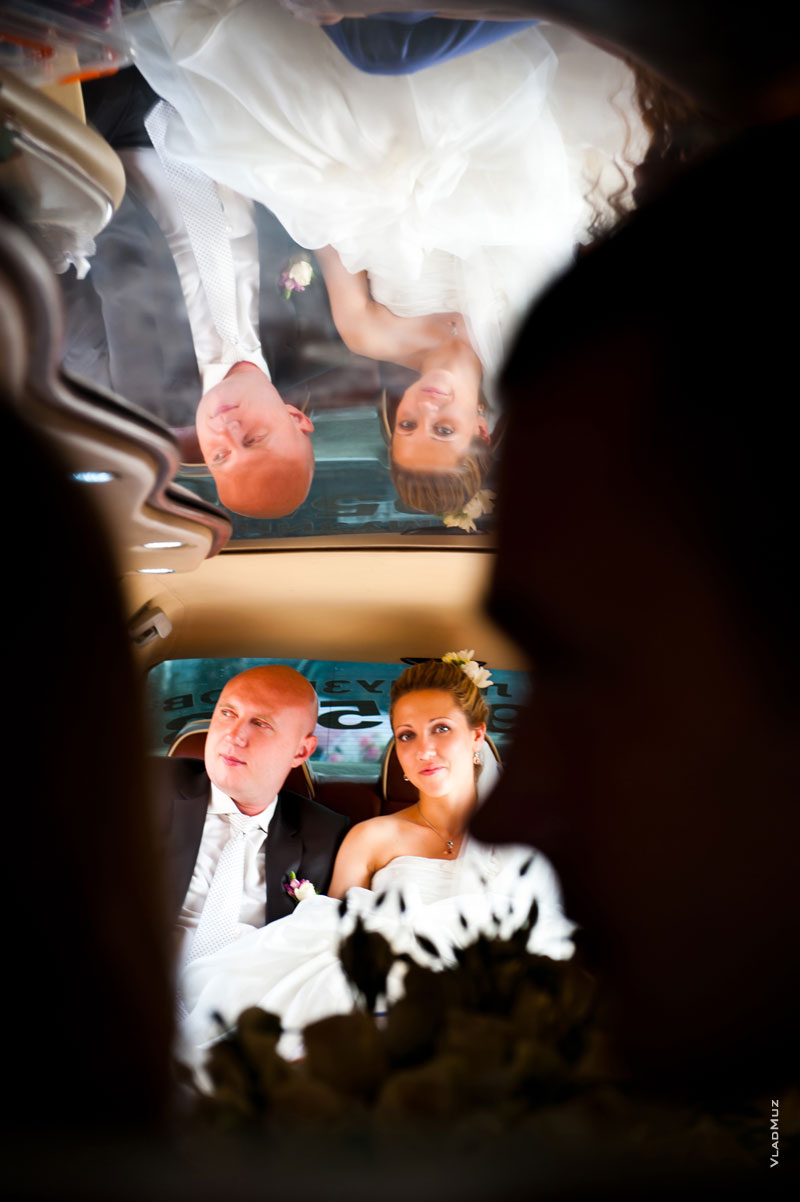 Фото жениха с невестой и их отражения в зеркальной крыше свадебного лимузина
