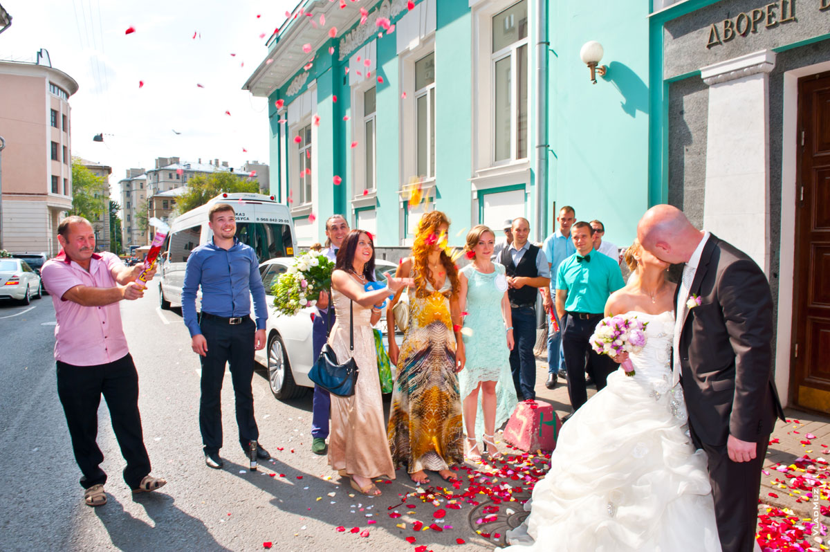 Фото свадебного поцелуя жениха и невесты у входа в Грибоедовский ЗАГС под залп из хлопушек