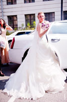Фото невесты в свадебном платье с длинным шлейфом у двери свадебного лимузина