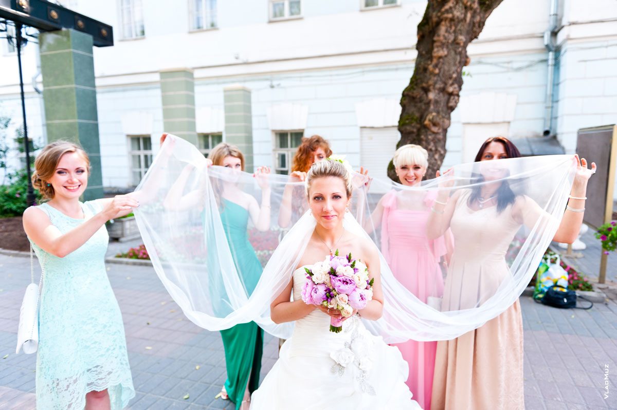 Прикольное фото невесты и подружек невесты с длинной, расправленной фатой в руках