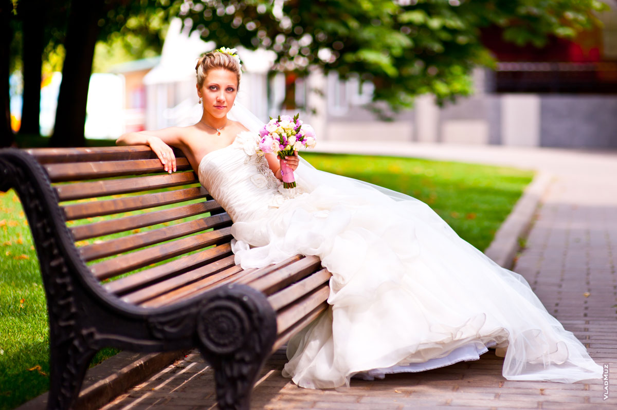Фото невесты с букетом хорошо показывает длинный шлейф красивого свадебного платья