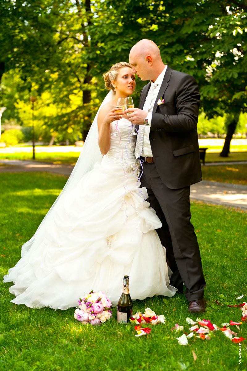 Фото жениха с невестой, стоящих на лужайке с бокалами шампанского
