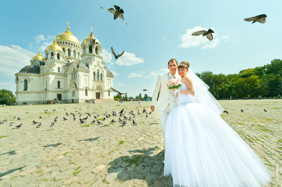Свадебная фотография жениха и невесты на фоне Вознесенского Кафедрального собора и стаи голубей