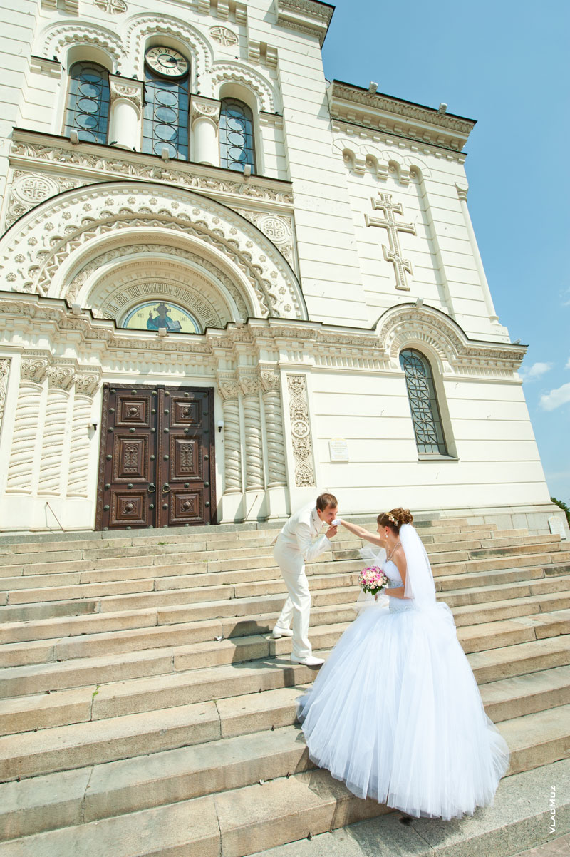 Фото жениха на ступенях перед собором в Новочеркасске, целующего невесте руки