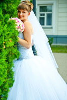 Яркий фотопортрет невесты с букетом у зеленой туи