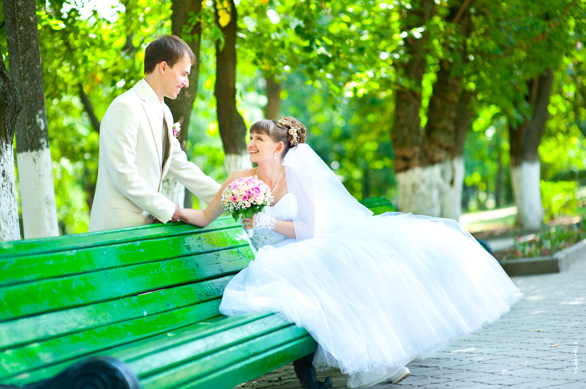 Фото невесты на лавочке и жениха перед невестой в Александровском парке Новочеркасска