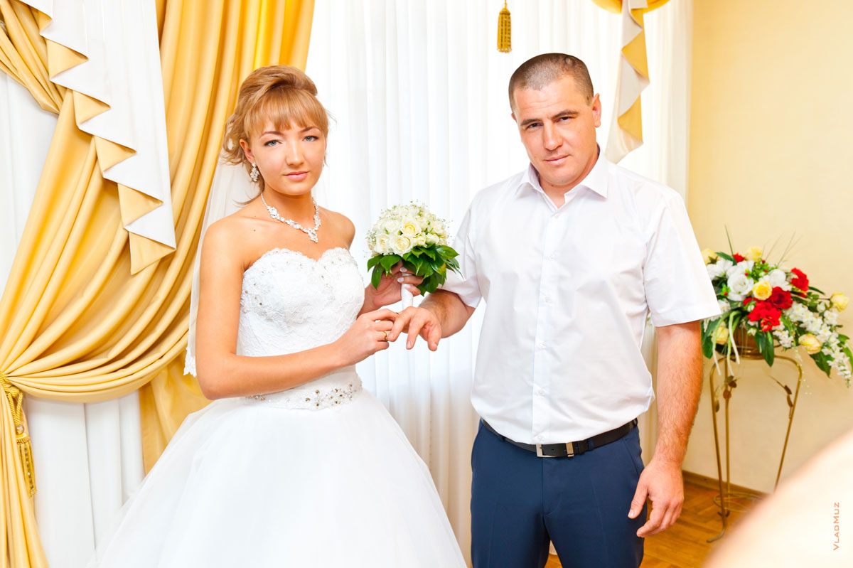 Фото жениха с невестой во время обмена обручальными кольцами в ЗАГСе